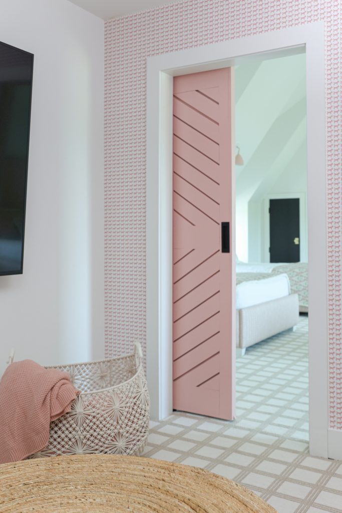 Luxury interior design by Kirkendall Design in Tulsa, OK featuring a barn door painted Benjamin Moore’s Eraser Pink opening to a secret hideout with playful dog-patterned wallpaper.