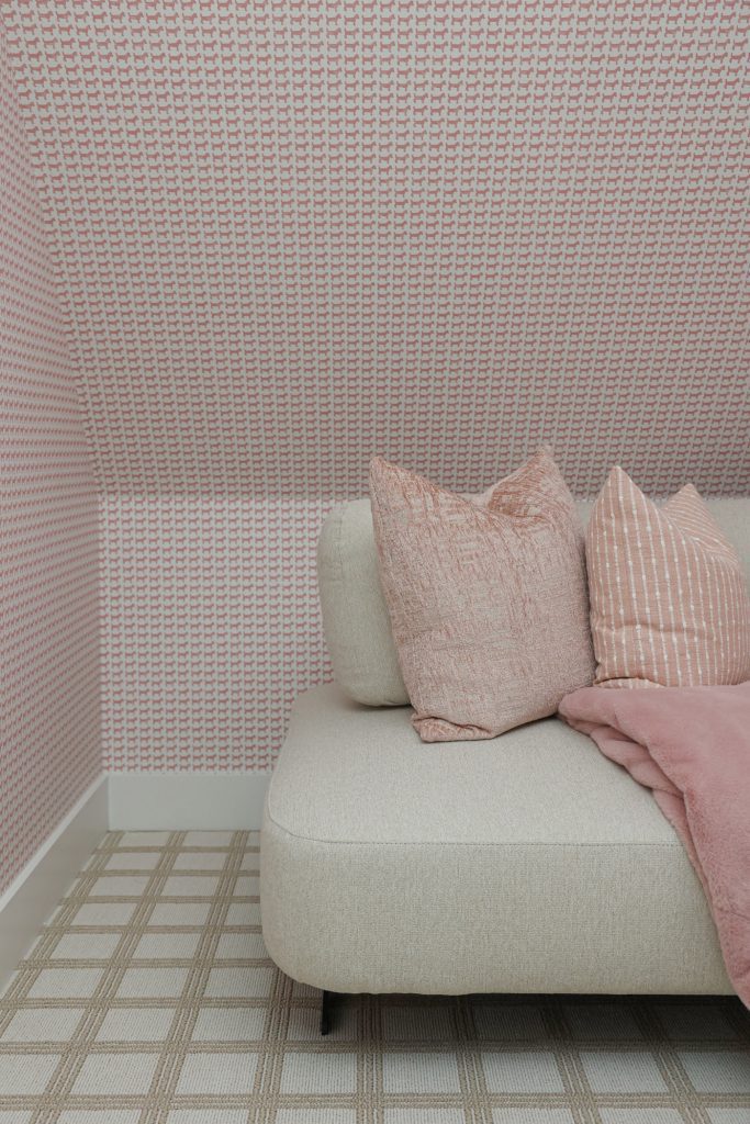 Luxury interior design by Kirkendall Design in Tulsa, OK showing a cozy hideout with a sofa, neutral windowpane-patterned carpet, and playful dog-themed wallpaper.