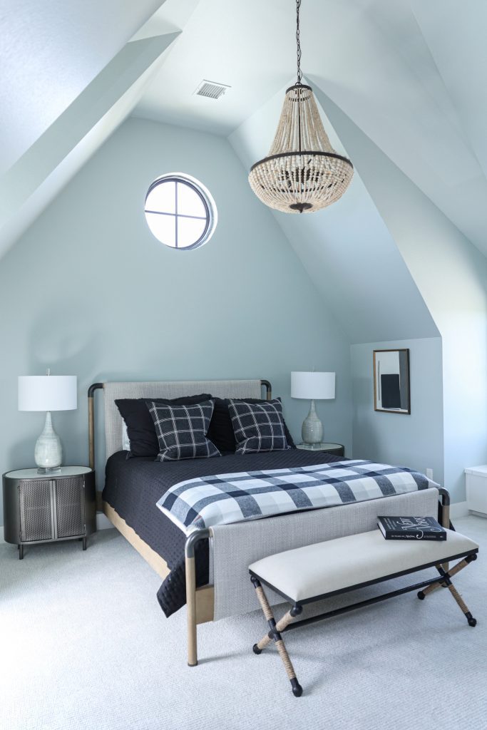 Luxury interior design by Kirkendall Design in Tulsa, OK featuring a boys’ bedroom with a neutral palette of black, white, grey, and taupe, a wooden chandelier, oval metal nightstands, and a bed with fabric stretched over a wood and pipe frame.