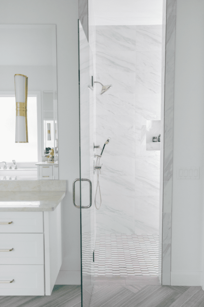 white marble walk in shower glass shower door interior design by Kirkendall Design in Tulsa, OK