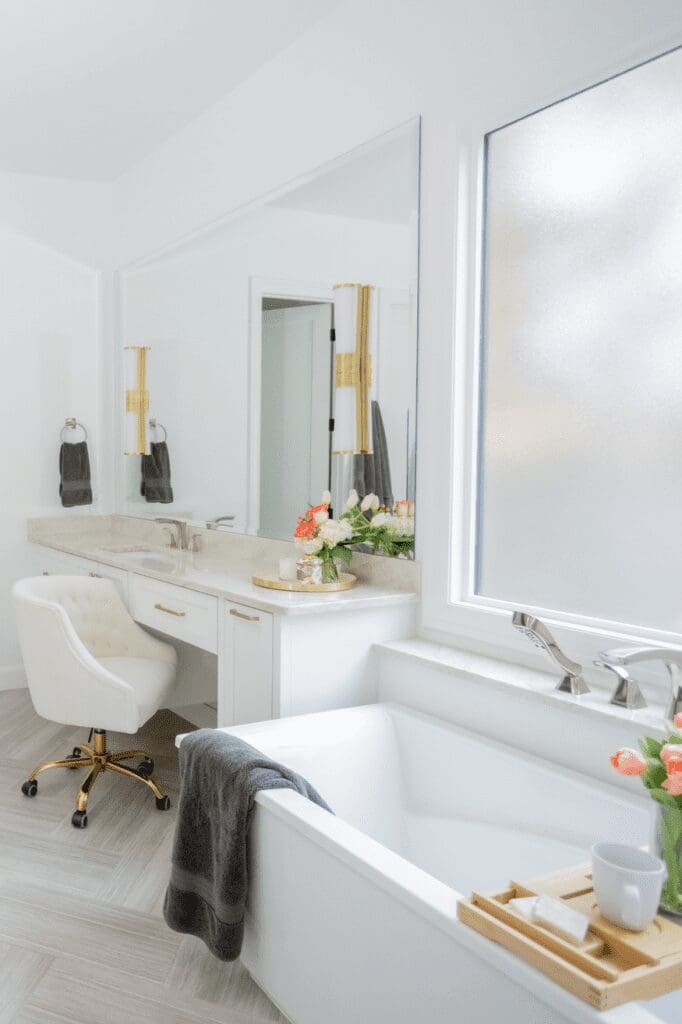 bright bathroom with frosted window, free standing tub and white vanity interior design by Kirkendall Design in Tulsa, OK