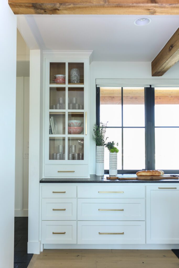 Luxury kitchen design by Kirkendall Design in Tulsa, OK featuring illuminated cabinet shelves displaying a collection of heirloom dishes, artfully arranged between cabinetry mullions.