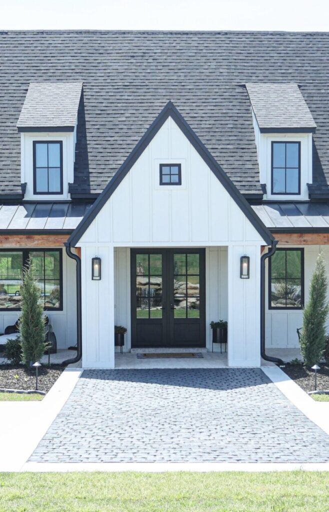 Luxury interior design by Kirkendall Design in Tulsa, OK showcasing the exterior of a new construction farmhouse-style home with cedar posts, pine ceilings, batten board siding, black frame windows, and metal roofing, blending rustic charm with classic sophistication.