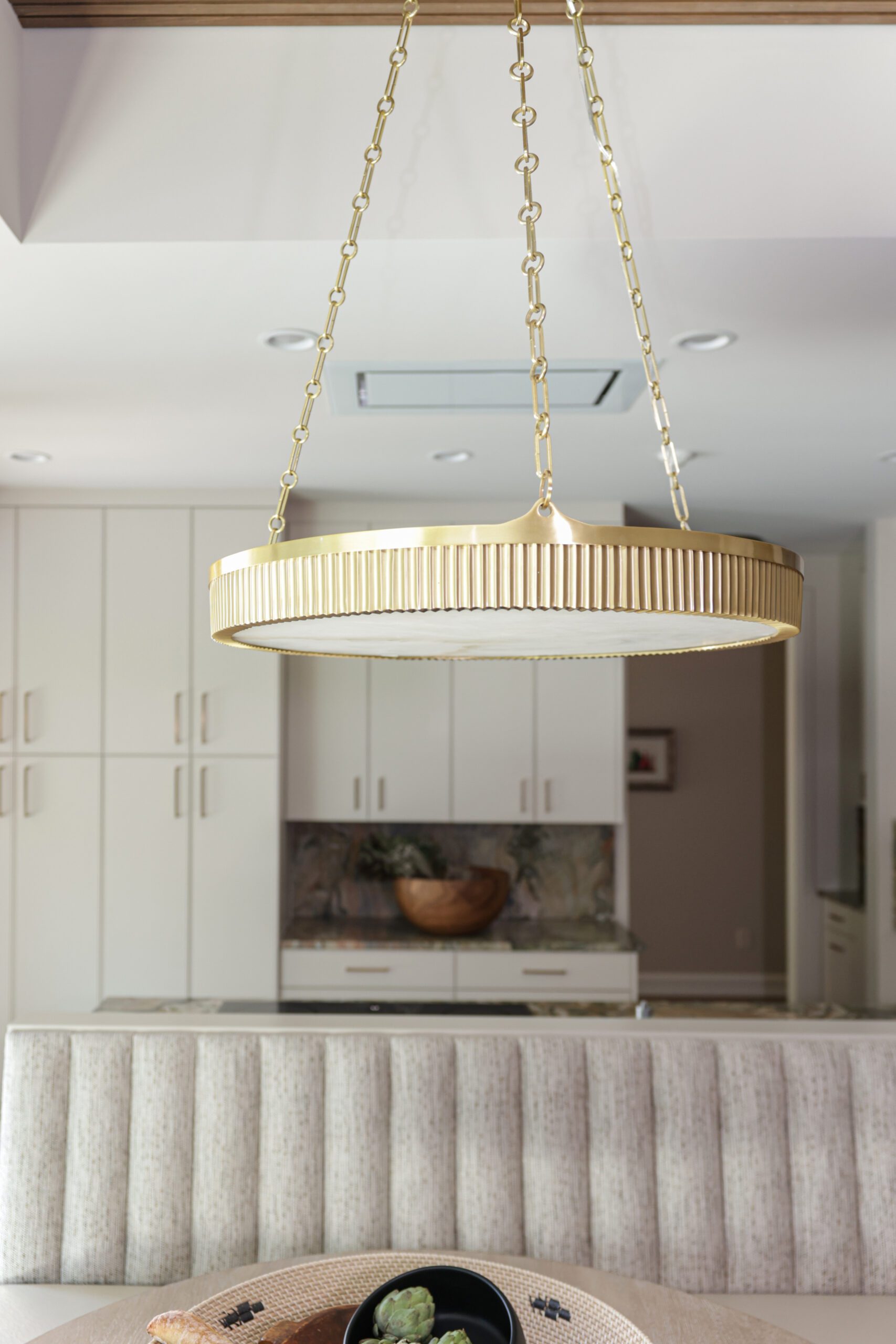 gold light fixture hanging over custom banquette, interior design by Kirkendall Design