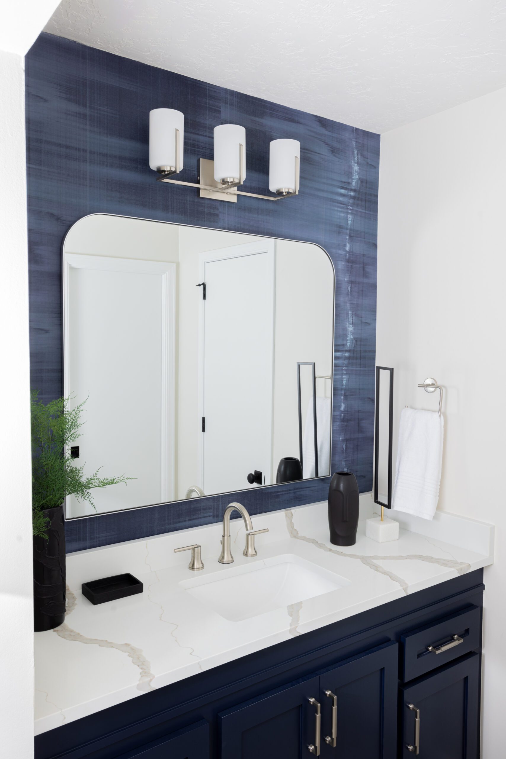 Boys bathroom design with dark blue wallpaper by Kirkendall Design