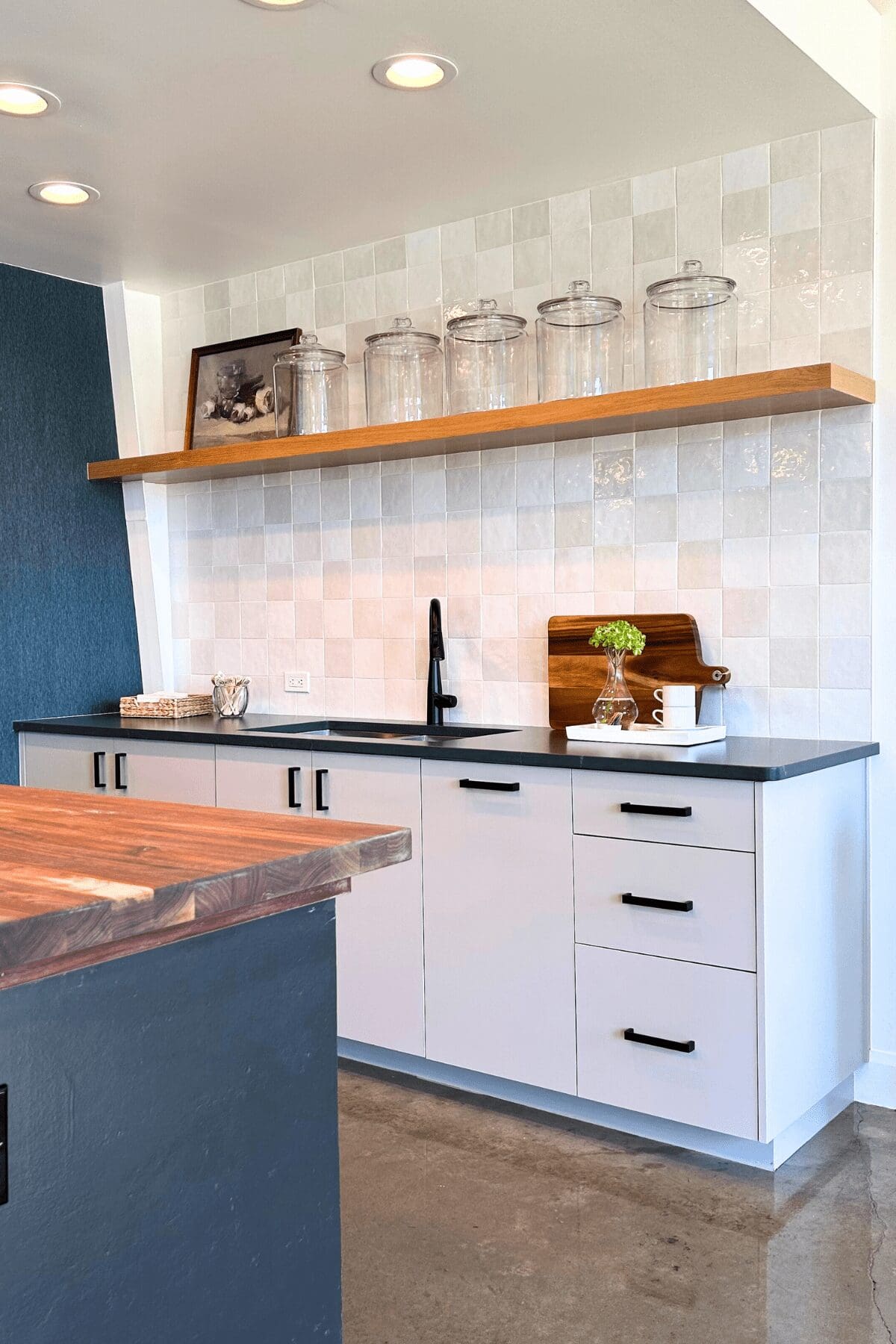 two-tone backsplash paired with blue wallpaper and floating shelf in small kitchen, commercial interior design by Kirkendall Design