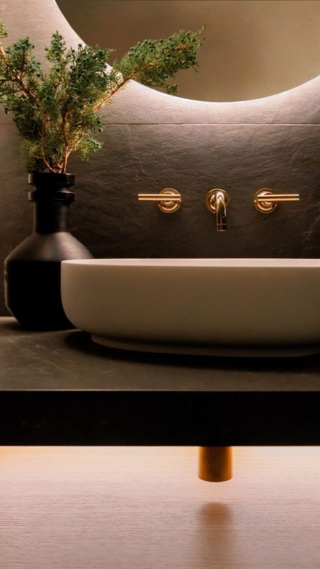 NKBA 2025 award-winning bathroom featuring a black tile backsplash, backlit mirror, and vessel sink.