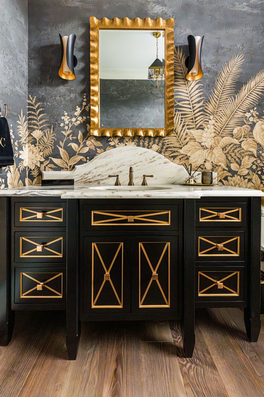 NKBA 2025 award-winning powder bath featuring a curved backsplash, large-scale gold-leaf wallcovering, a black vanity, and gold accents.