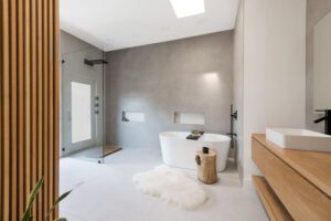NKBA 2025 award-winning primary bathroom with spacious, spa-like layout featuring large-format concrete-look tile and minimalist design.
