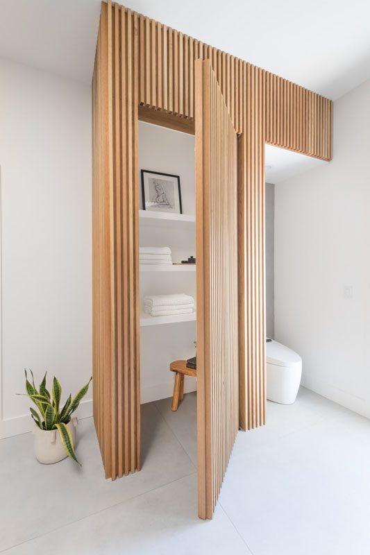NKBA 2025 award-winning primary bathroom featuring a hidden closet door within a tambour wall made of white oak slats.