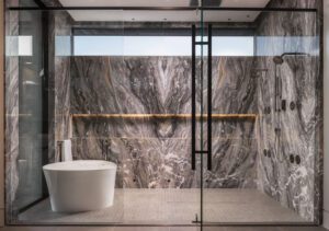 NKBA 2025 award-winning primary bathroom featuring marble-lined wet room with high narrow window.