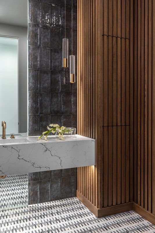 NKBA 2025 award-winning powder bath featuring a teak panel wall, full-height tiled backsplash, and a floating white quartz vanity with black veining.