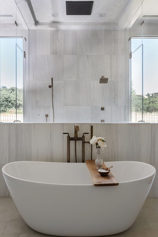 NKBA 2025 award-winning primary bathroom featuring a pony wall shower and a tiled ceiling with a rainhead shower system.