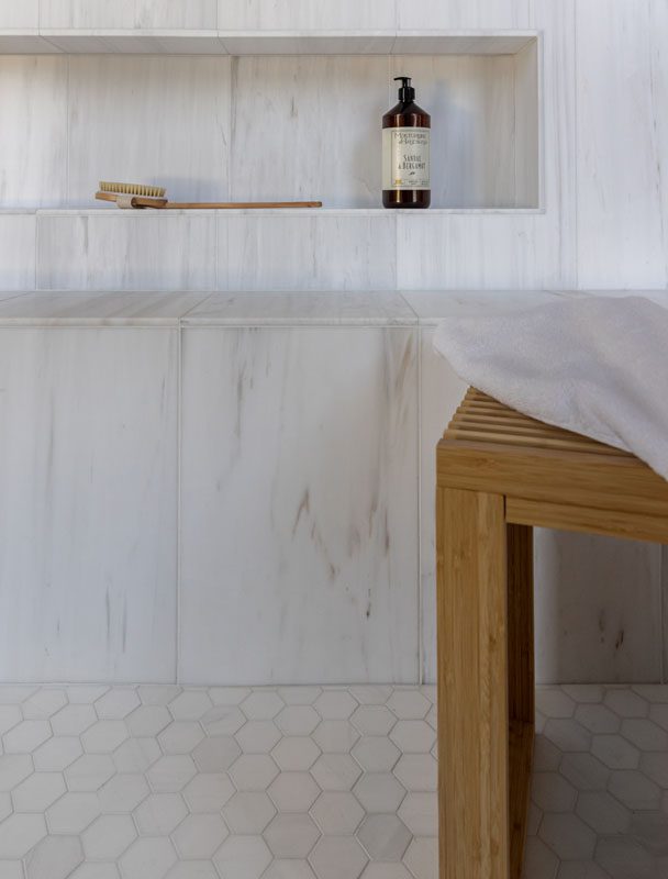 Close up of the shower in the NKBA 2025 award-winning primary bathroom, featuring a mix of honed marble and fabric-effect ceramic tiles.