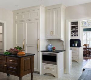 Refrigerator area in French country kitchen with small custom island and pantry in background