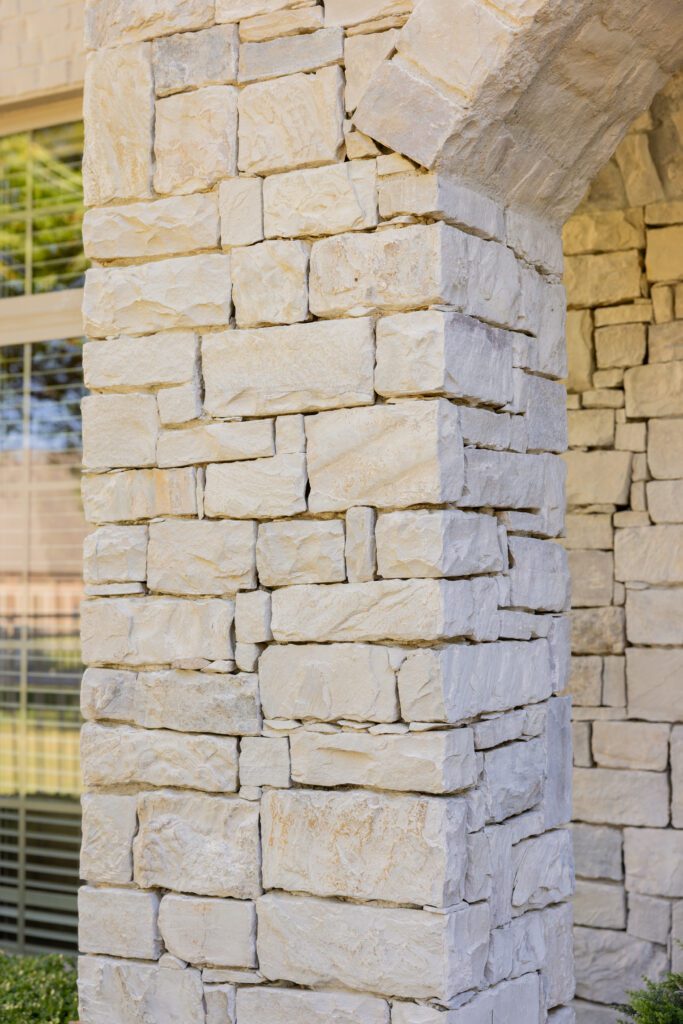 Close‑up of brown fieldstone exterior refreshed with limewash paint on Tulsa home