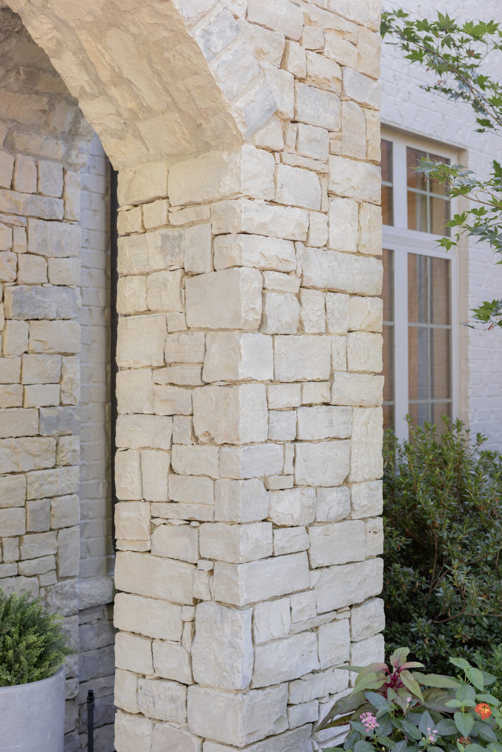 Close‑up of brown fieldstone exterior refreshed with light limewash paint on Tulsa home