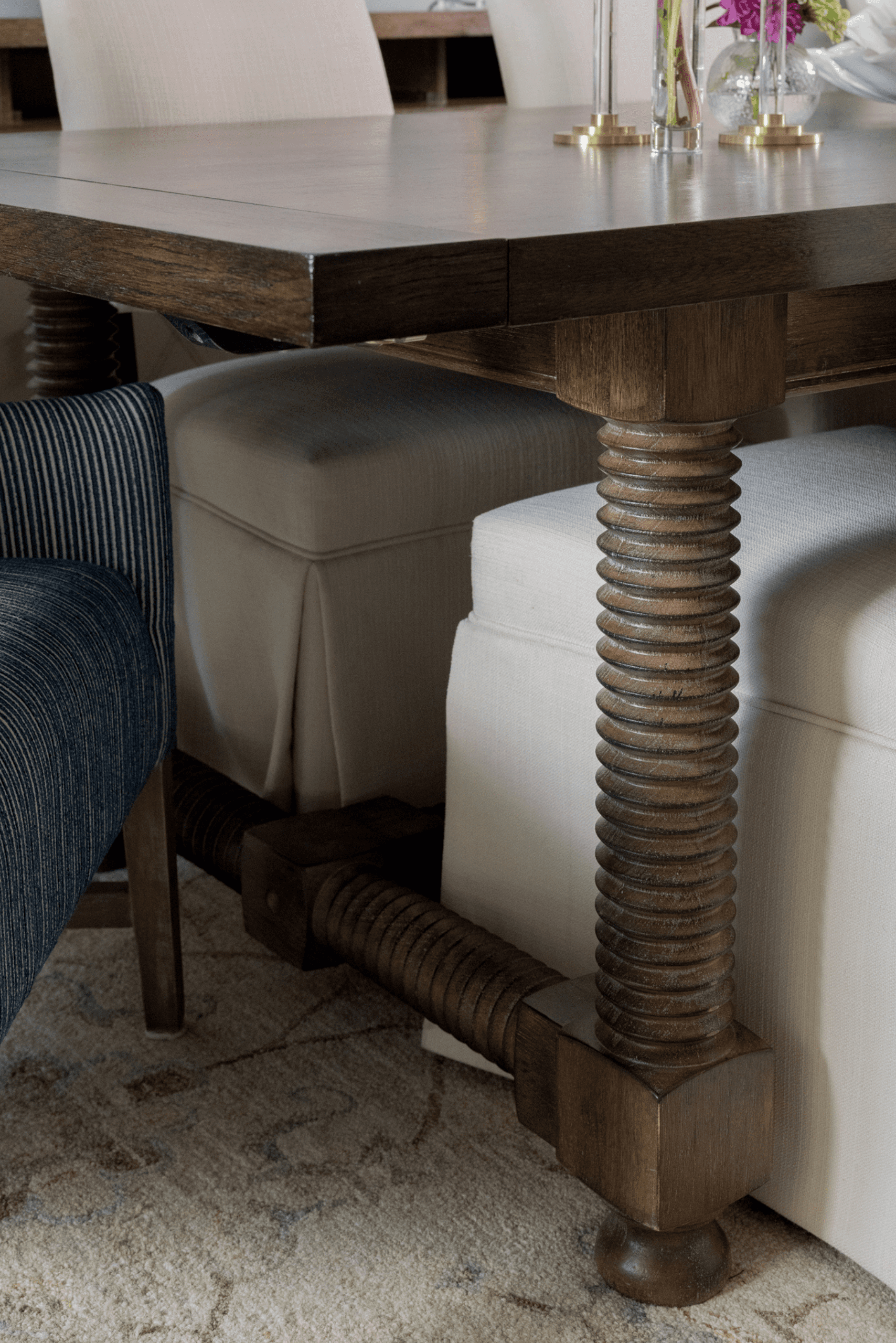 Luxury interior design by Kirkendall Design in Tulsa, OK featuring a refreshed dining room with the clients’ existing table paired with new upholstered chairs, blue striped head chairs for contrast, and reframed artwork that elevates the space.