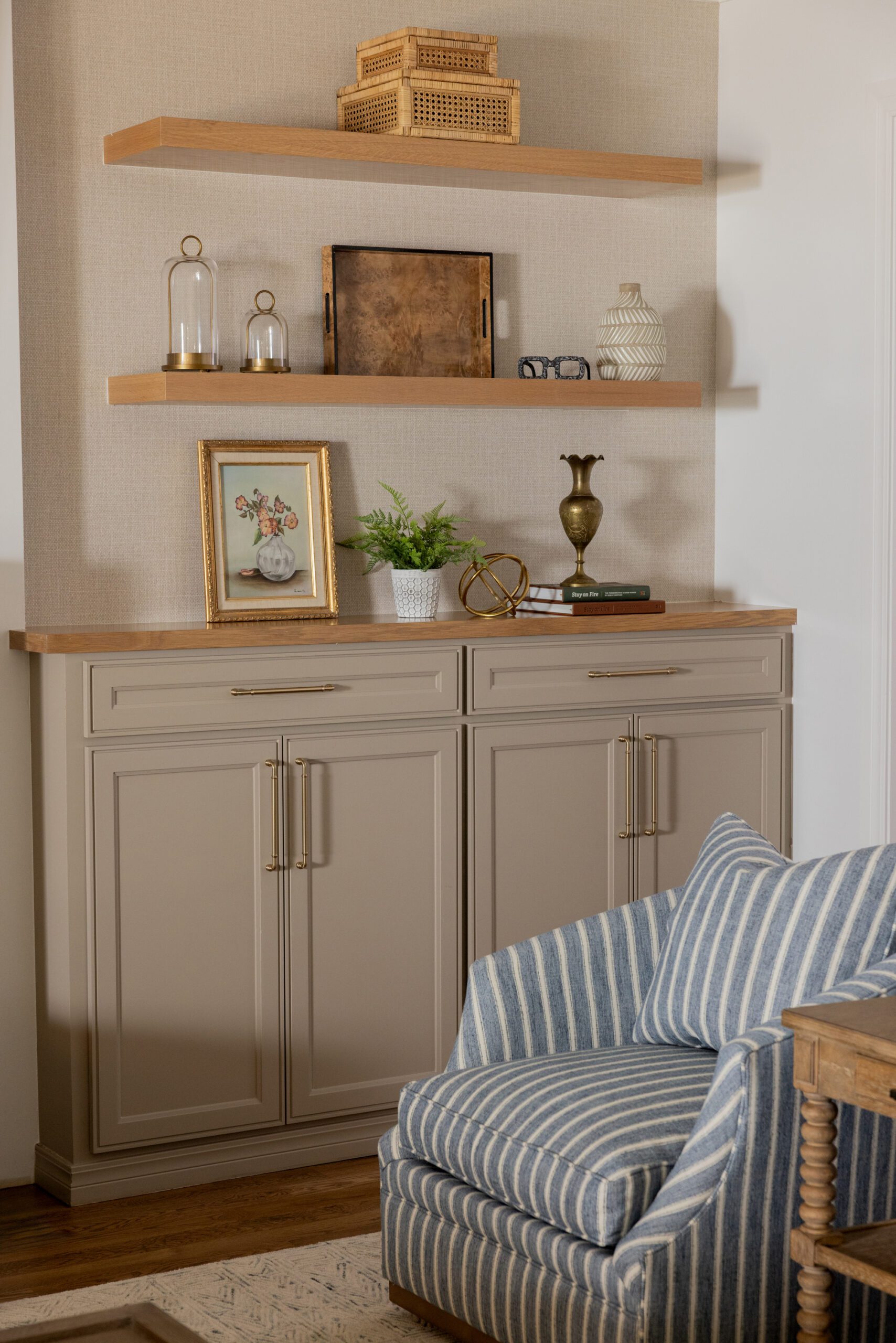 Luxury interior design by Kirkendall Design in Tulsa, OK showing a main-level renovation and full-service interior design living room, picture is the remodeled stone fireplace with custom built-ins, layered seating, and a collected Nancy Meyers–inspired aesthetic in soft blues, greens, and creams.