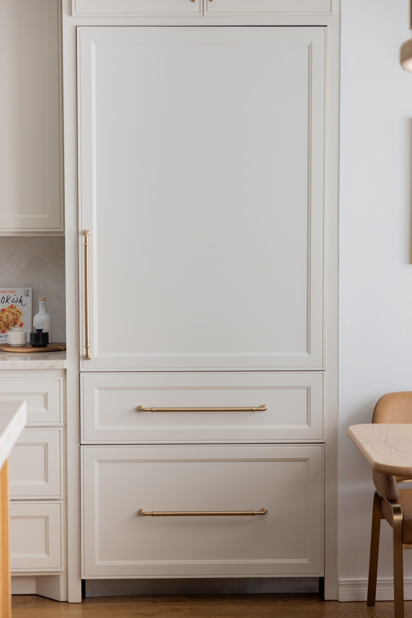 Luxury interior design by Kirkendall Design in Tulsa, OK showcasing an integrated refrigerator seamlessly built into soft neutral kitchen cabinetry for a clean, streamlined look in a renovated kitchen.