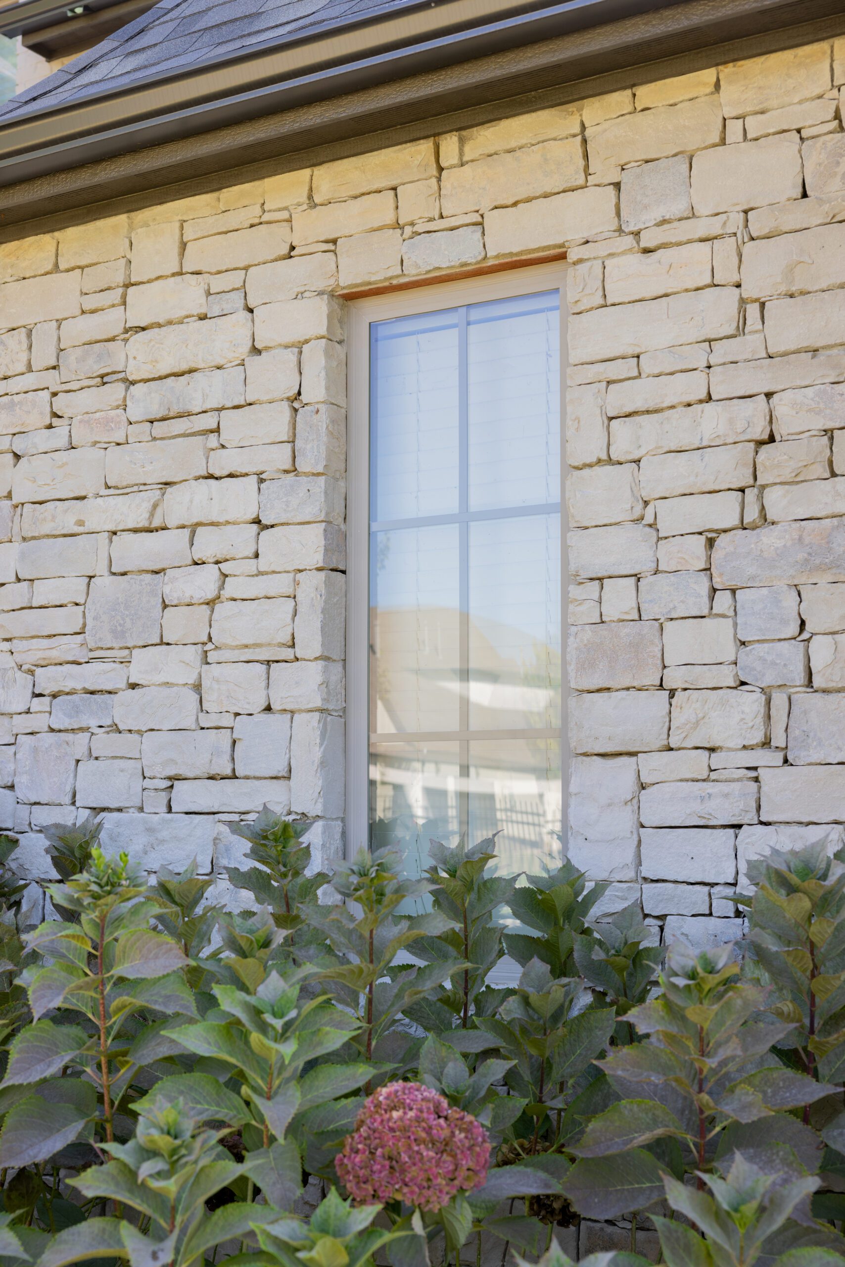 Side view of limewashed stone facade on Southern Oaks Tulsa residence without shutters