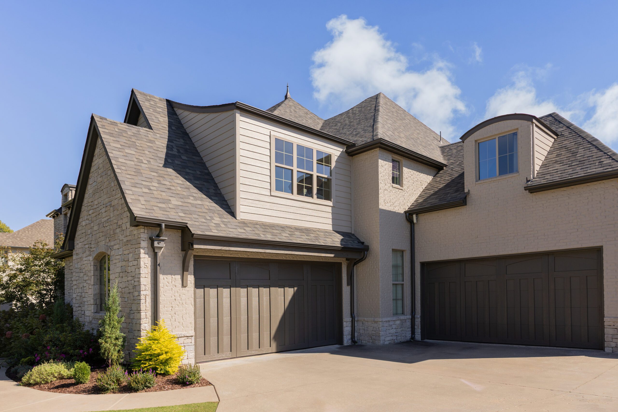 Side view of limewashed stone facade on Southern Oaks Tulsa residence with new garage door