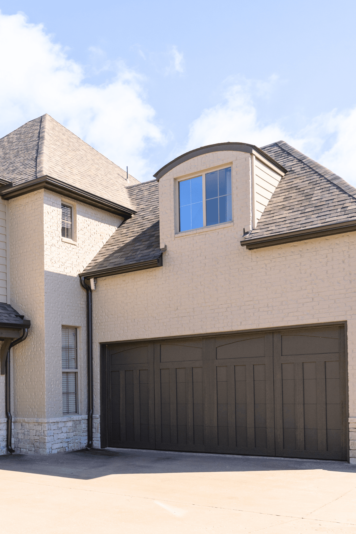 Side view of Tulsa home after limewash, featuring new garage door and limewashed brick and stone exterior