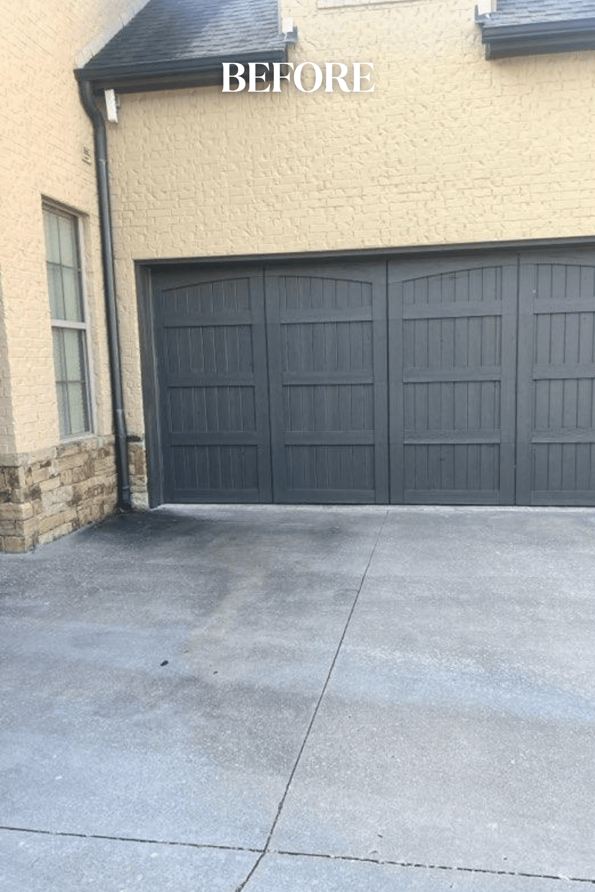 Side view of Tulsa home before limewash, showing old garage door, tan brick, and discolored stone skirting along the bottom