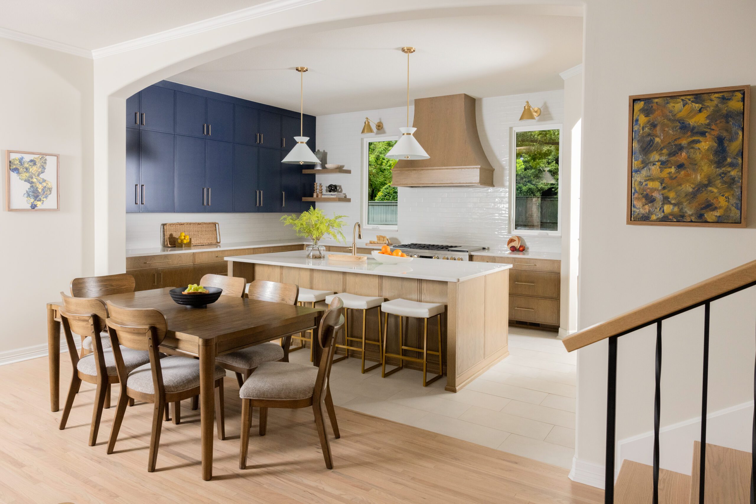 Custom Tulsa kitchen renovation featuring two-tone cabinetry with stained lower cabinets, deep blue upper cabinets, a large island, full-height tile backsplash, and luxury finishes.
