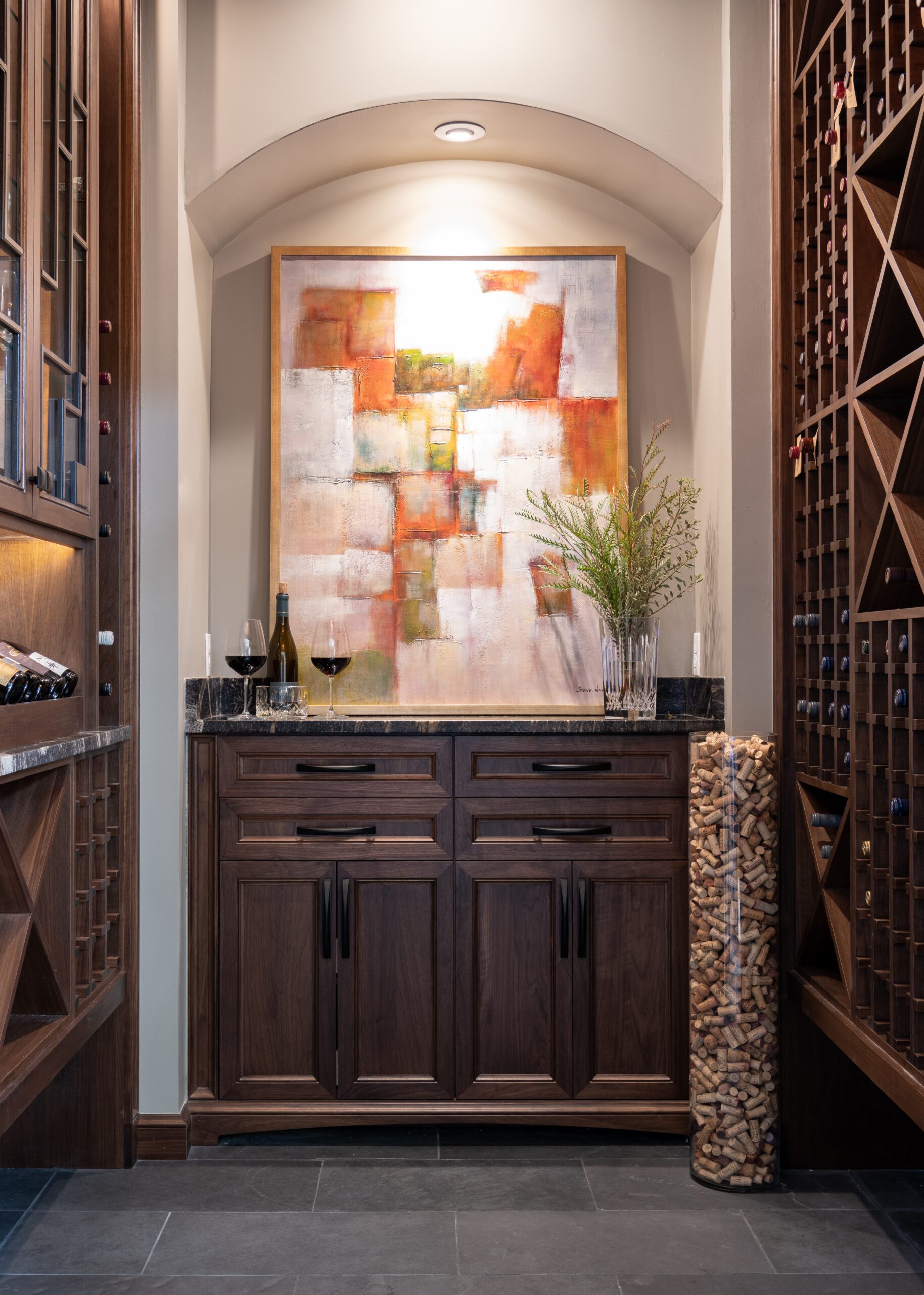Custom wine room designed by Kirkendall Design featuring built-in wine storage, moody finishes, and collected decor transformed from an unused patio space in this luxury Tulsa home renovation.