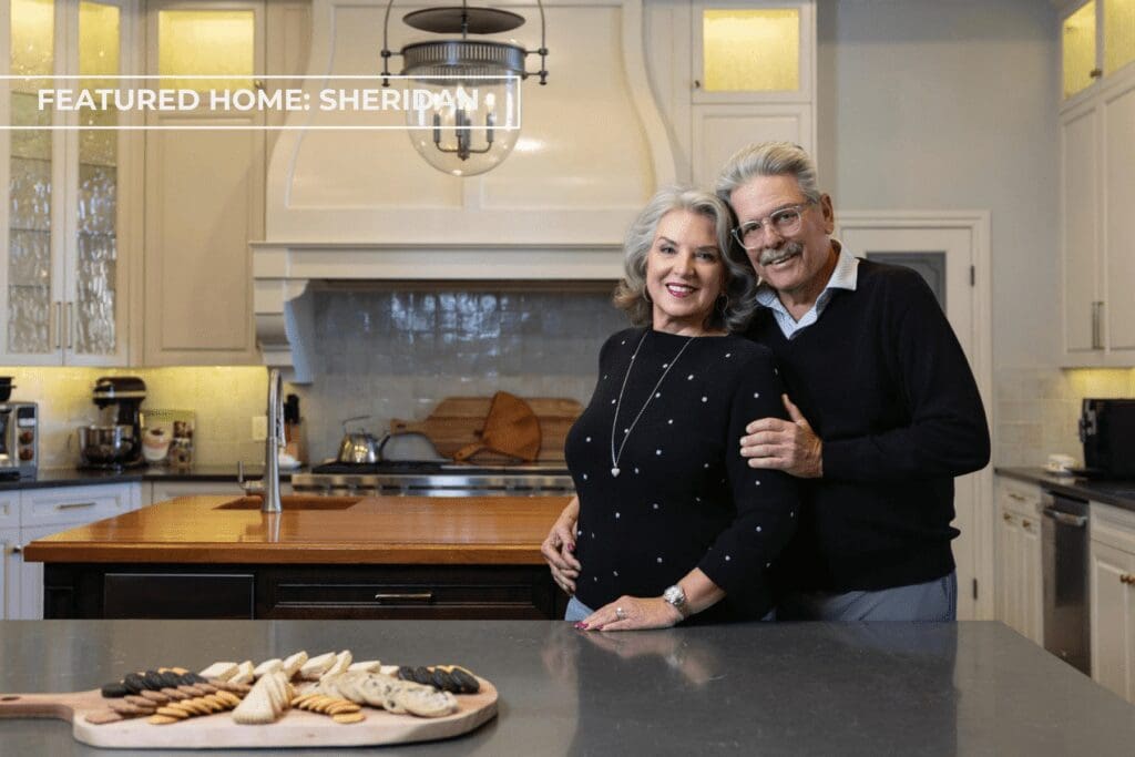 Bernie and Christine Sheridan standing in their luxury kitchen renovation inside their multigenerational Tulsa home designed by Kirkendall Design, featuring custom cabinetry, layered textures, and collected artwork inspired by their travels throughout Asia.