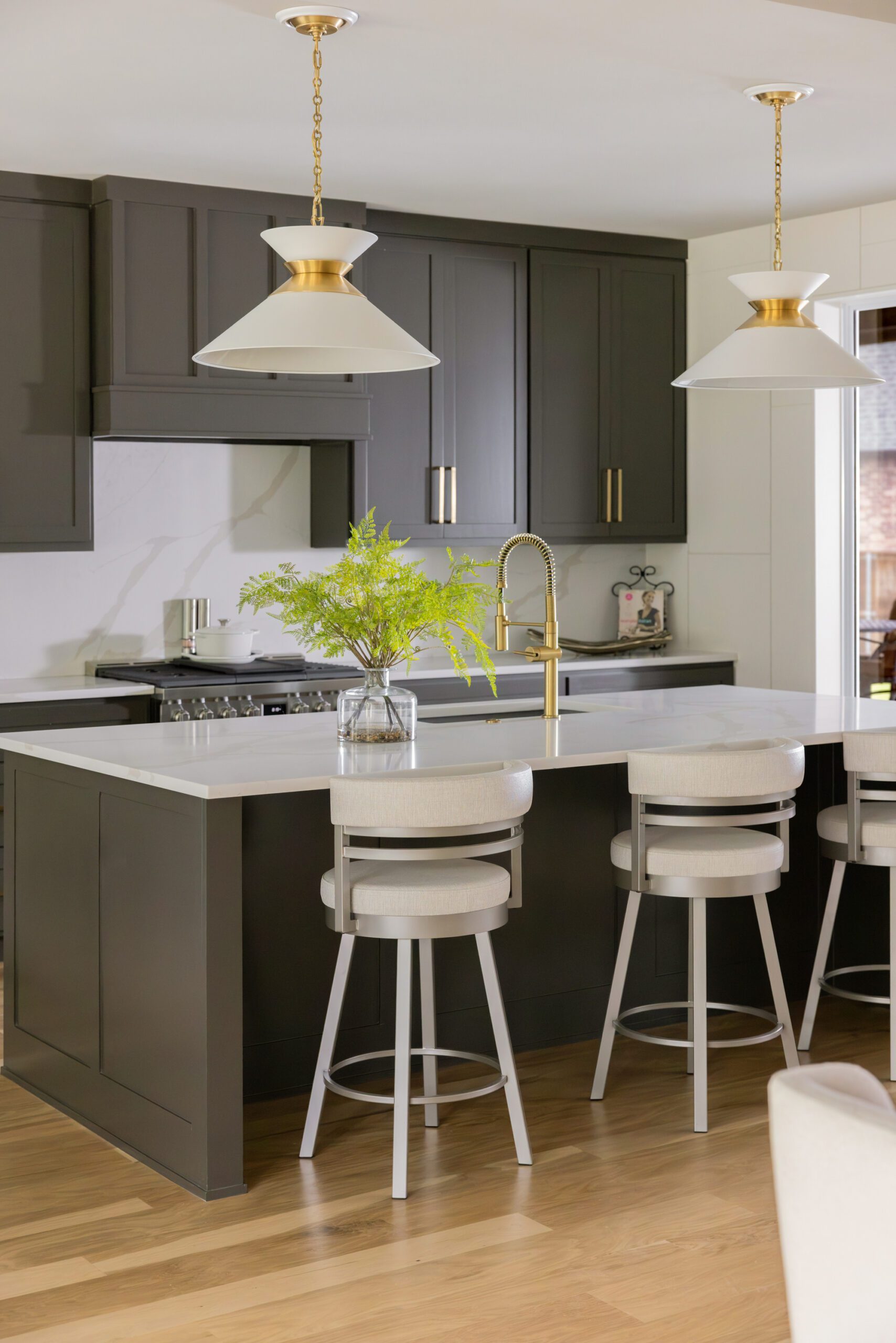 Tulsa interior design kitchen update featuring rich chocolate brown painted cabinetry, modern white and gold pendant lighting, and elevated details creating a custom kitchen feel, design by Kirkendall Design