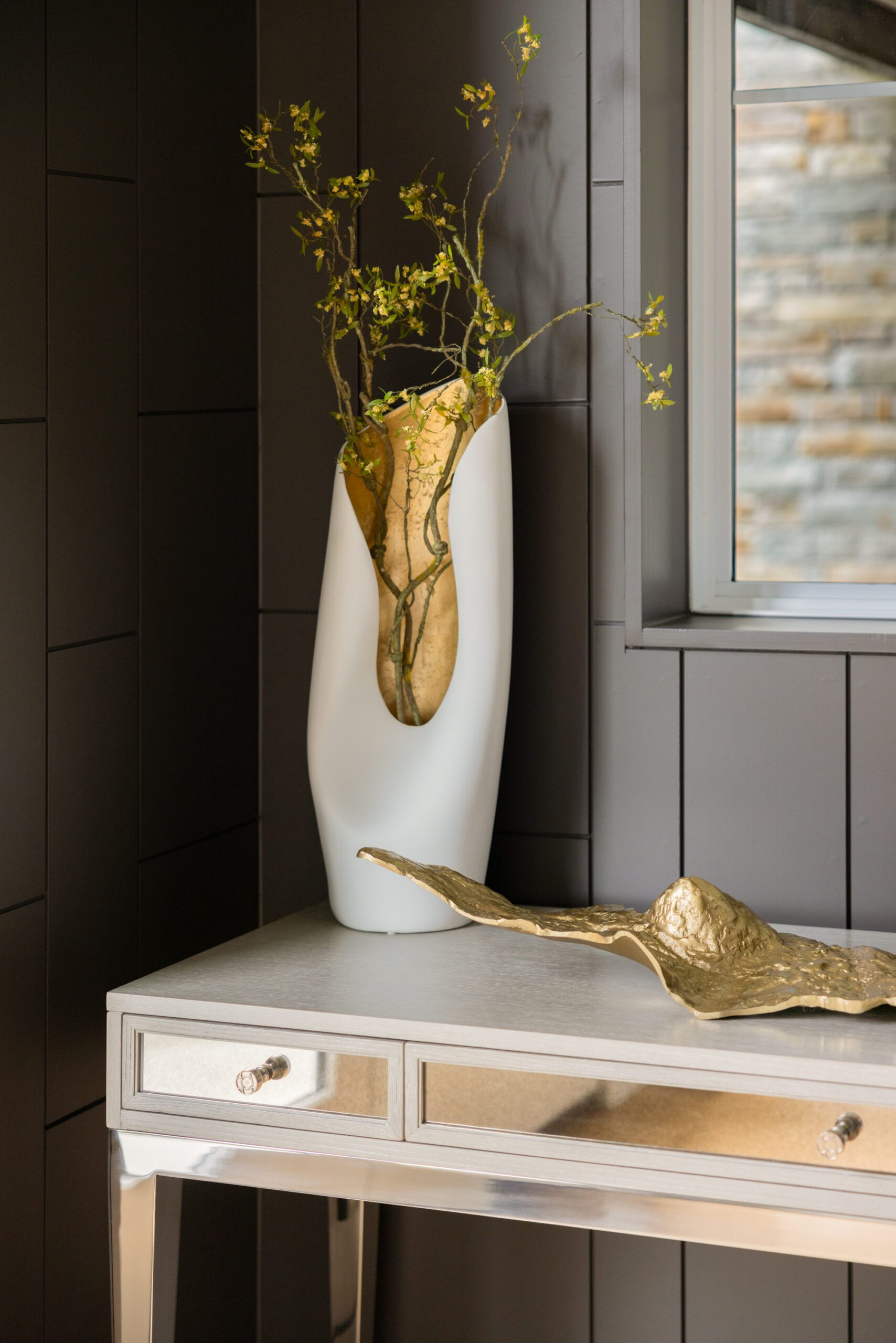 Tulsa interior design entryway detail featuring styled decor on a console table inside a custom chocolate brown alcove creating a warm, personalized new build foyer