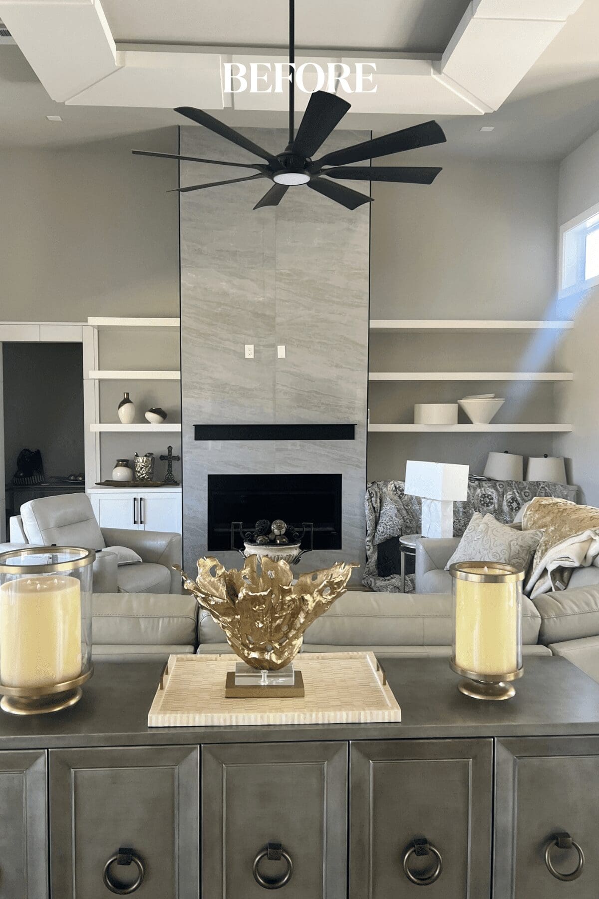 Before photo of a new construction home living room with all-white built-ins, floating shelves, and ceiling treatment before interior design updates by Kirkendall Design