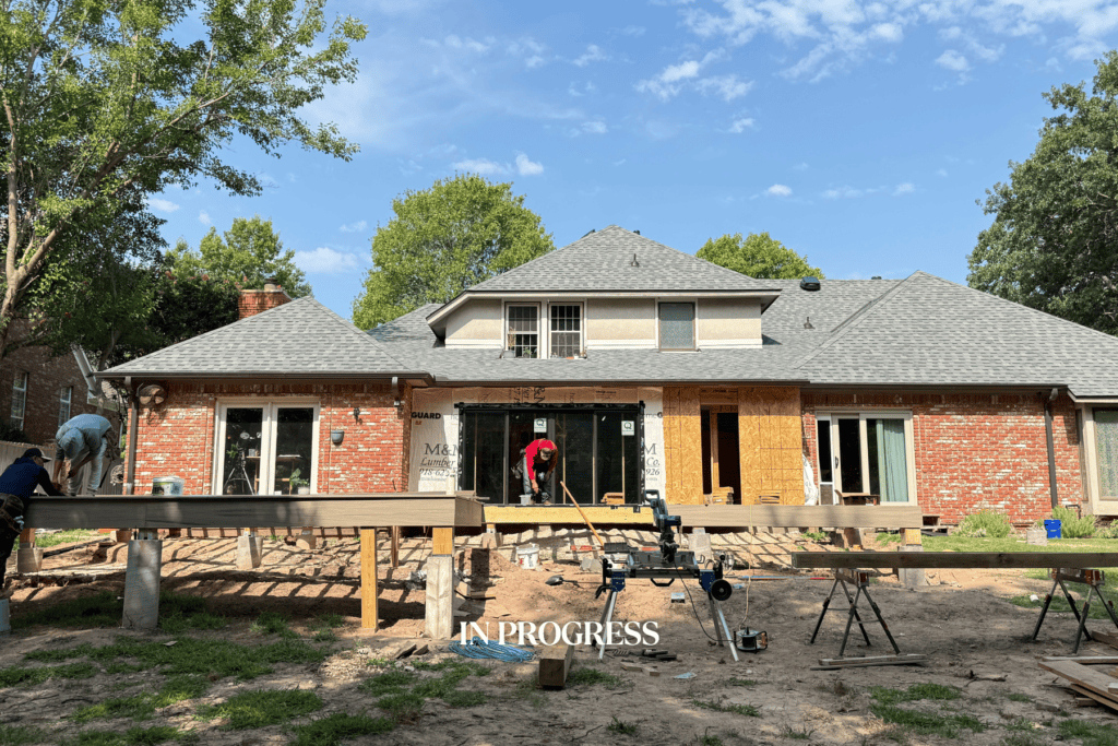 Construction progress of a Tulsa outdoor living renovation by Kirkendall Design showing the expanded deck, outdoor kitchen framing, and fireplace installation.