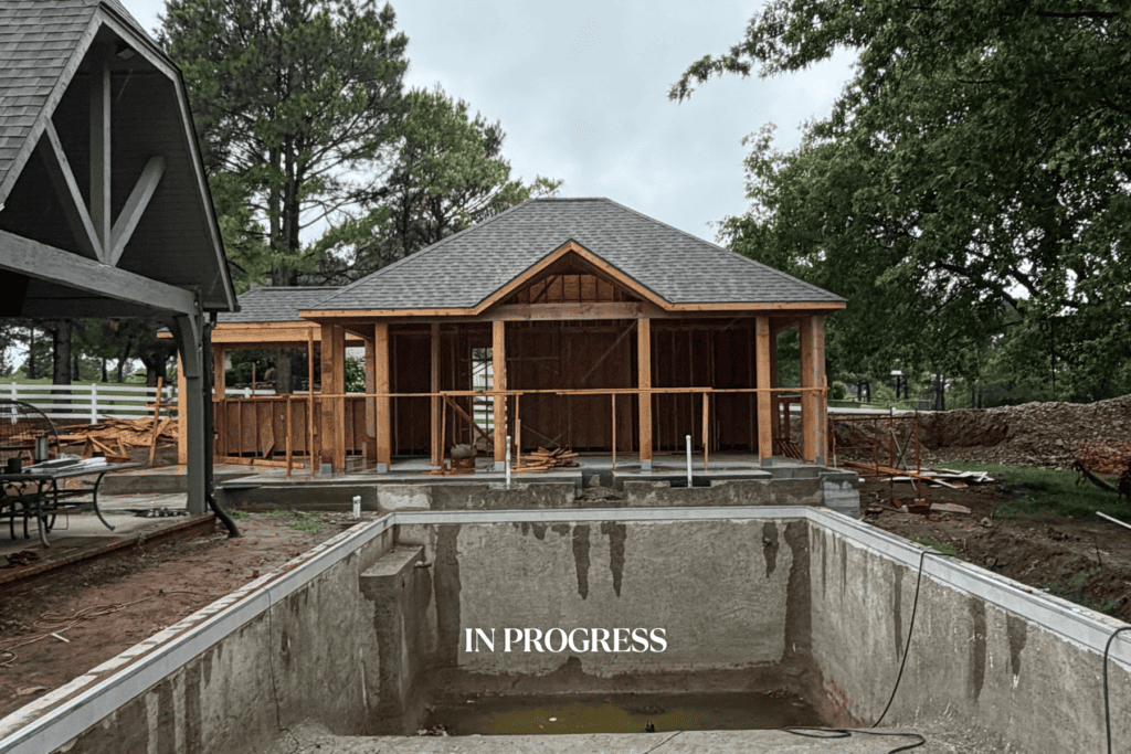 Construction progress of a custom pool cabana by Kirkendall Design showing pool installation, cabana framing, and roof construction in Tulsa, Oklahoma.