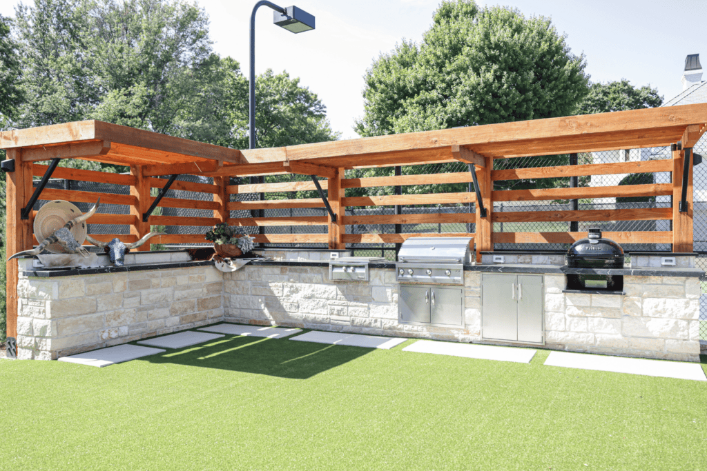 Completed outdoor kitchen by Kirkendall Design featuring built-in appliances, brick finishes, turf landscaping, and an entertaining space in Tulsa, Oklahoma.