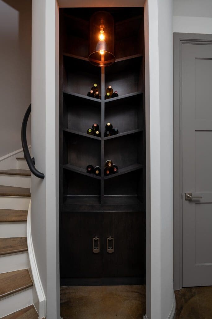 Custom black built-in wine display designed by Kirkendall Design, featuring angled geometric shelving that adds an architectural element to the space.